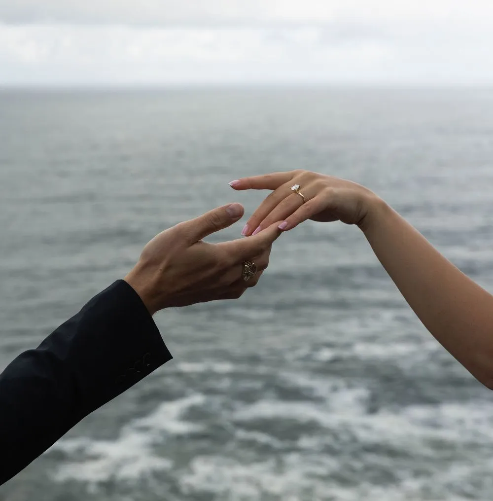 Hands meeting with a ring above the sea