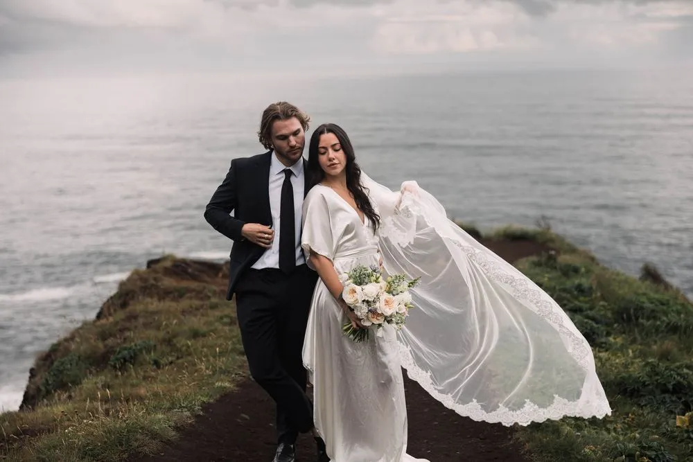 A couple on a coastal cliff at golden hour, photographed by Holly Rogers
